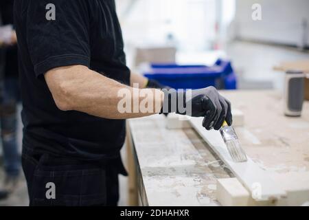 Senior worker painting wooden box while standing in industry Stock Photo