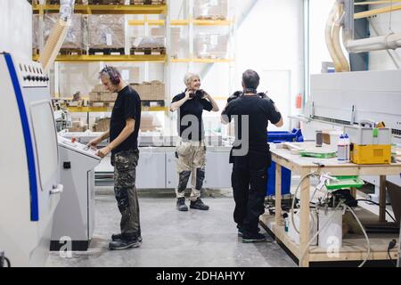 Full length of workers communicating while working at industry Stock Photo