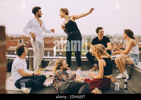 Happy people dancing while enjoying music with friends on terrace at rooftop party Stock Photo