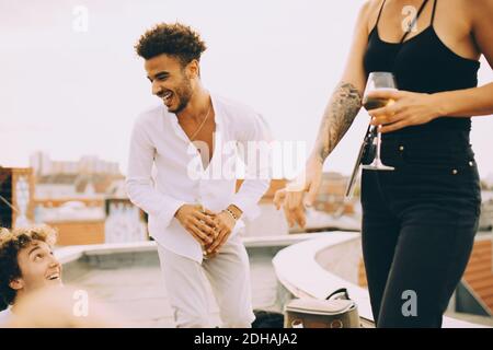 Happy young man dancing and enjoying drinks with friends on terrace at party Stock Photo