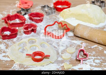 Cutting out cookies from the dough and various molds lying on the table. Selective focus Stock Photo