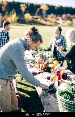 Male farmer using digital tablet at table with friends in background Stock Photo