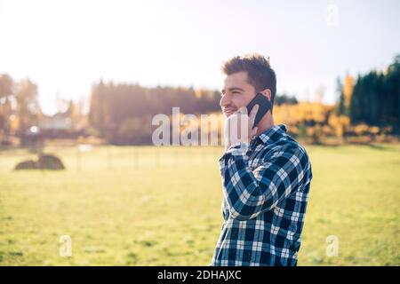 Mid adult male farmer talking on mobile phone on field Stock Photo