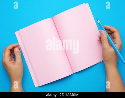Two female hands holding open notepad with empty pink sheets Stock Photo