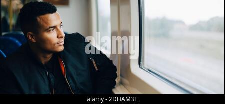 Man injecting insulin while sitting by window in train Stock Photo