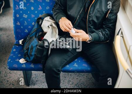Midsection of man doing blood test while sitting in train Stock Photo
