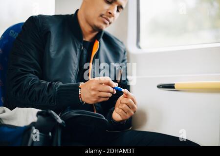 Man doing blood test while sitting in train Stock Photo