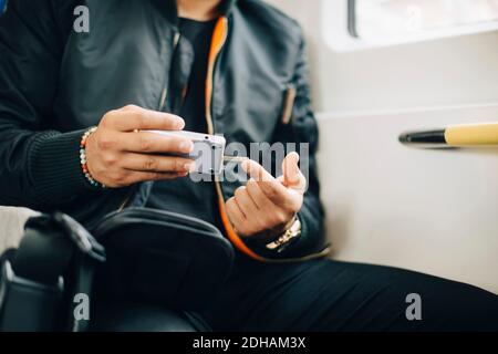 Man doing blood test with glaucometer while sitting in train Stock Photo