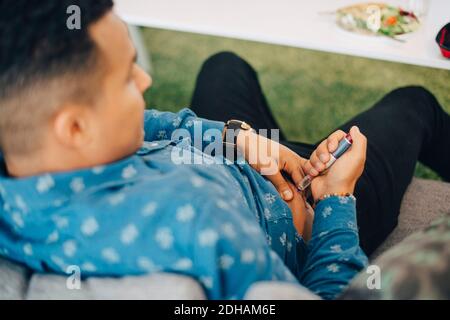 High angle view of businessman injecting insulin while sitting on sofa in office Stock Photo