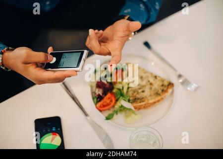 Businessman checking blood sugar level with glaucometer while having food at table Stock Photo