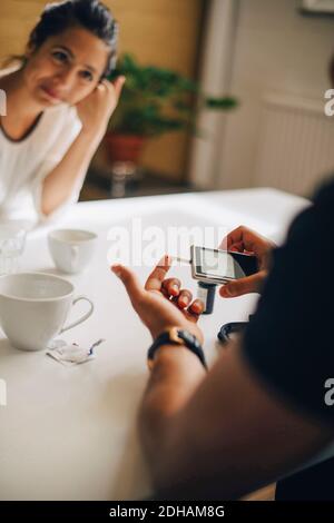 Cropped image of businessman checking blood sugar level on glaucometer at table Stock Photo