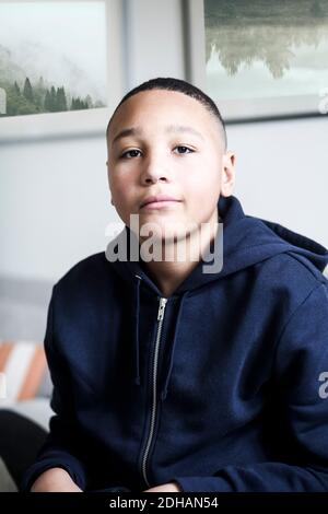 Portrait of teenage boy wearing hooded jacket at home Stock Photo