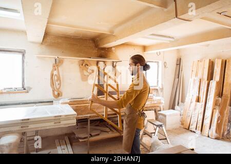 Handsome carpenter checking the quality of the window frame before the paint at the carpentry workshop