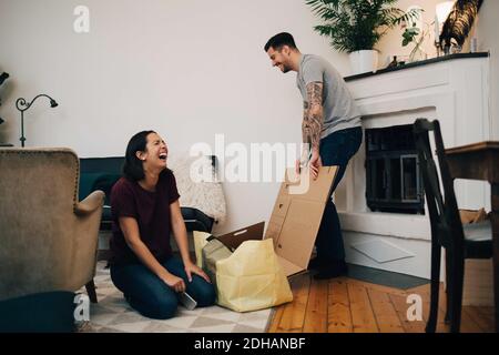 Cheerful couple unpacking boxes in living room at new home Stock Photo