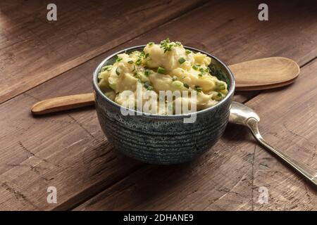 Pomme puree, a photo of a bowl of mashed potatoes with herbs on a rustic background with a wooden spoon Stock Photo