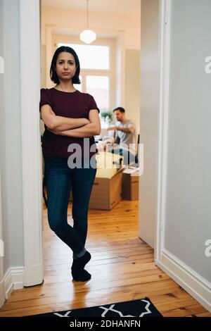 Portrait of mid adult woman with arms crossed leaning on doorway at new home Stock Photo
