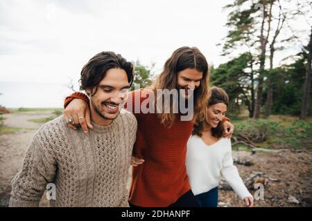 Smiling friends walking with arms around outdoors Stock Photo