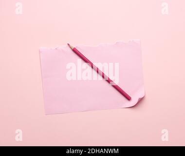 Blank pink torn sheet of paper from a notebook and a wooden pencil Stock Photo