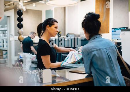 Sales woman showing color swatches to customer at hardware store Stock Photo