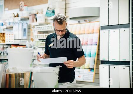 Mature male employee reading document in hardware store Stock Photo