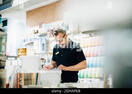 Salesman in uniform writing on document in hardware store Stock Photo