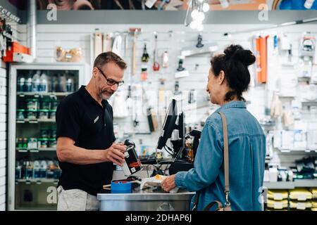 Male cashier talking with Customer at checkout counter in hardware store Stock Photo