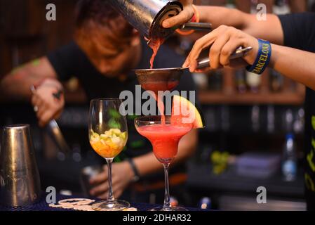 barman pouring alcohol cocktail in martini glasses for christmas party Stock Photo