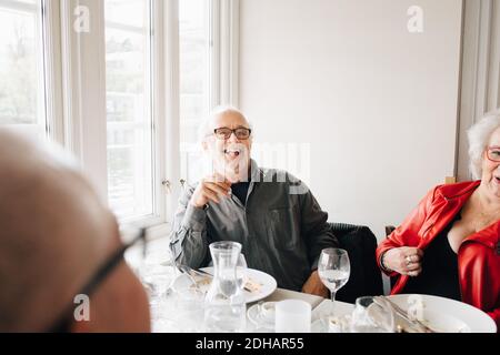 Happy Senior friends enjoying while sitting in restaurant Stock Photo