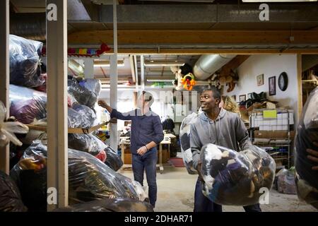Coworkers stacking plastic sacks in warehouse Stock Photo