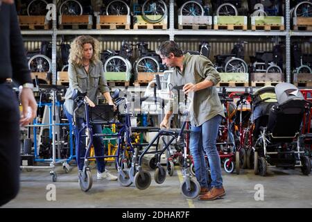 Full length of mature workers examining equipment at warehouse Stock Photo