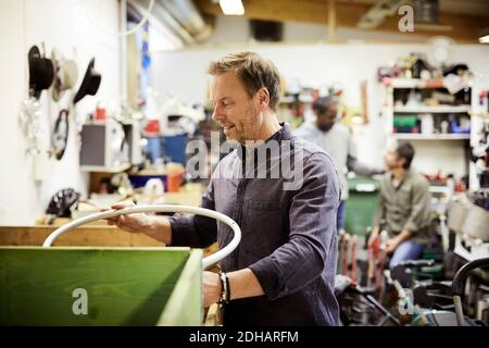 Smiling mature volunteer working against colleagues in workshop Stock Photo