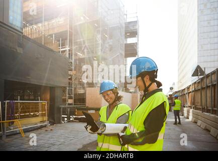 Female engineers discussing over digital tablet at construction site during sunny day Stock Photo