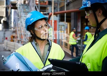 Female engineer discussing with coworker at construction site Stock Photo