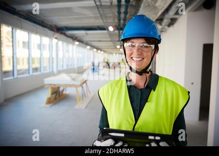Portrait of smiling female engineer in protective workwear at construction site Stock Photo