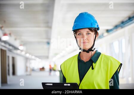 Portrait of confident female construction manager in reflective clothing at site Stock Photo