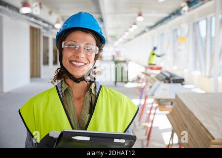 Portrait of smiling female foreman with digital tablet at construction site Stock Photo