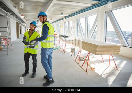 Full length of male and female engineers discussing at construction site Stock Photo