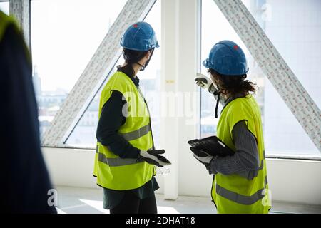 Side view of female engineers discussing at construction site Stock Photo