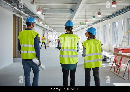 Rear view of male and female engineers walking at construction site Stock Photo