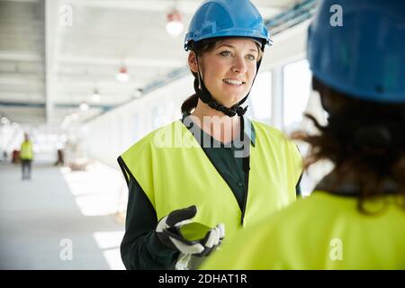 Confident female engineer discussing with coworker at construction site Stock Photo