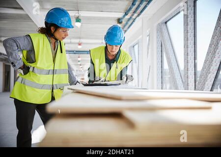 Female architects discussing over blueprint at construction site Stock Photo
