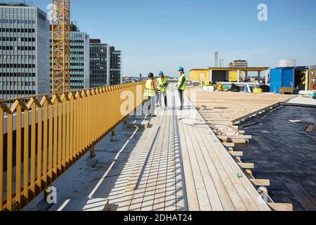 Male and female engineers discussing at construction site against sky Stock Photo