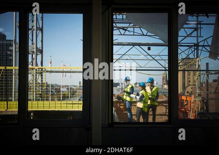 Male and female architects seen through window at construction site Stock Photo
