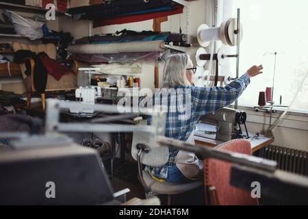 Senior owner using sewing machine at table in workshop Stock Photo