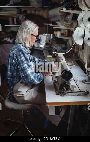Senior owner using sewing machine at workshop Stock Photo