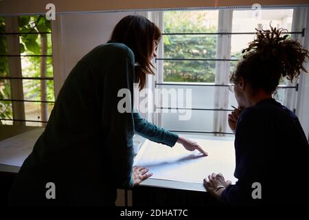 Female engineers discussing over blueprint at table in office Stock Photo
