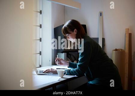 Side view of confident female architect using laptop in office Stock Photo