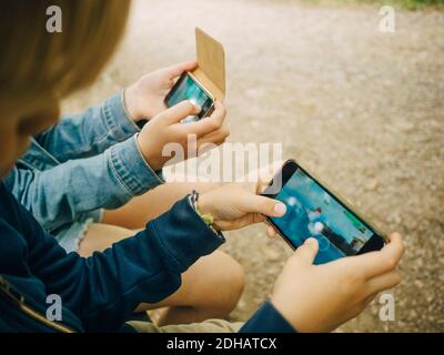 High angle view of siblings playing games on smart phone Stock Photo