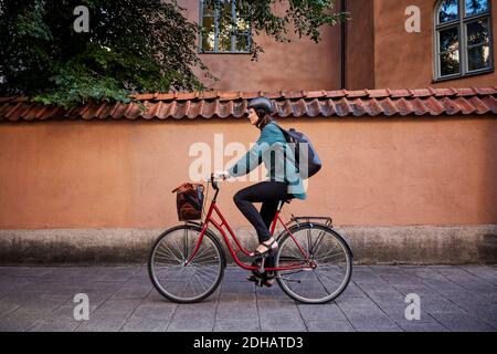Side view of female engineer riding bicycle on street in city Stock Photo