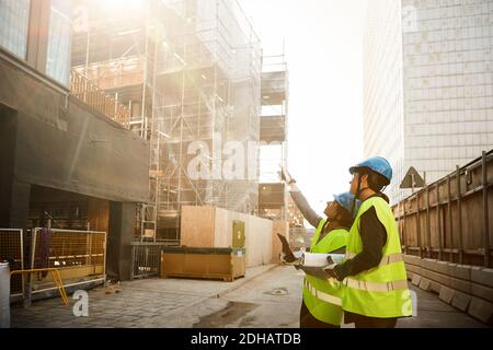 Female engineers in reflective clothing discussing at construction site Stock Photo